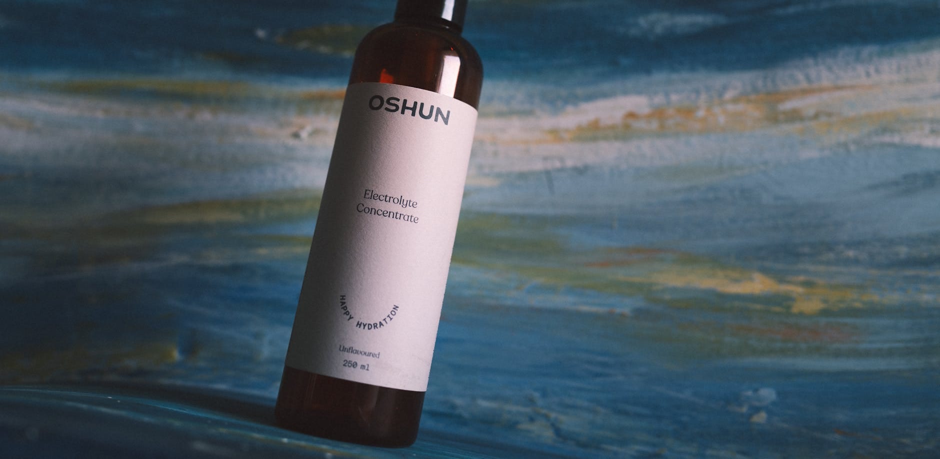 Butelka koncentratu elektrolitów Oshun na tle fakturowanej powierzchni